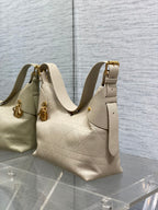 Cream quilted shoulder bag with gold top handles and side tab pocket
