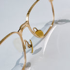 Gold eyeglasses temple close-up with small heart emblem on frame.