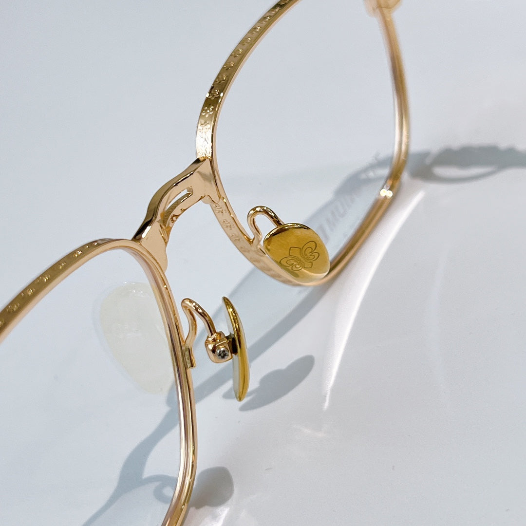 Gold eyeglasses temple close-up with small heart emblem on frame.