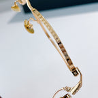 Gold eyeglasses temple close-up with ornate pattern and side detail.
