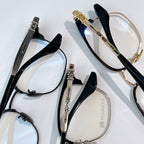 Assorted eyeglasses with black and gold frames, blue-tinted lenses, clear lenses