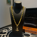 Gold chain necklace with cross pendant on display stand