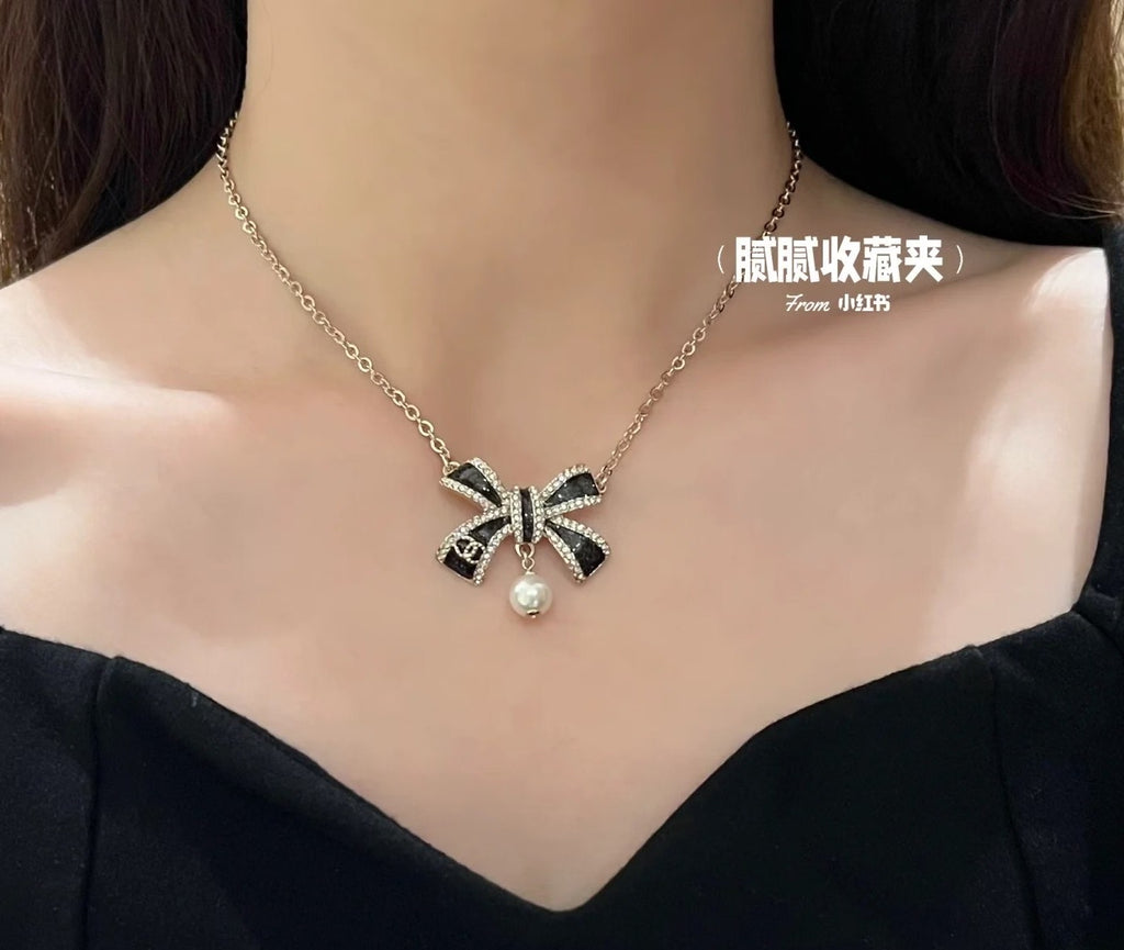 Gold necklace on model with ribbon bow pendant and pearl drop at center