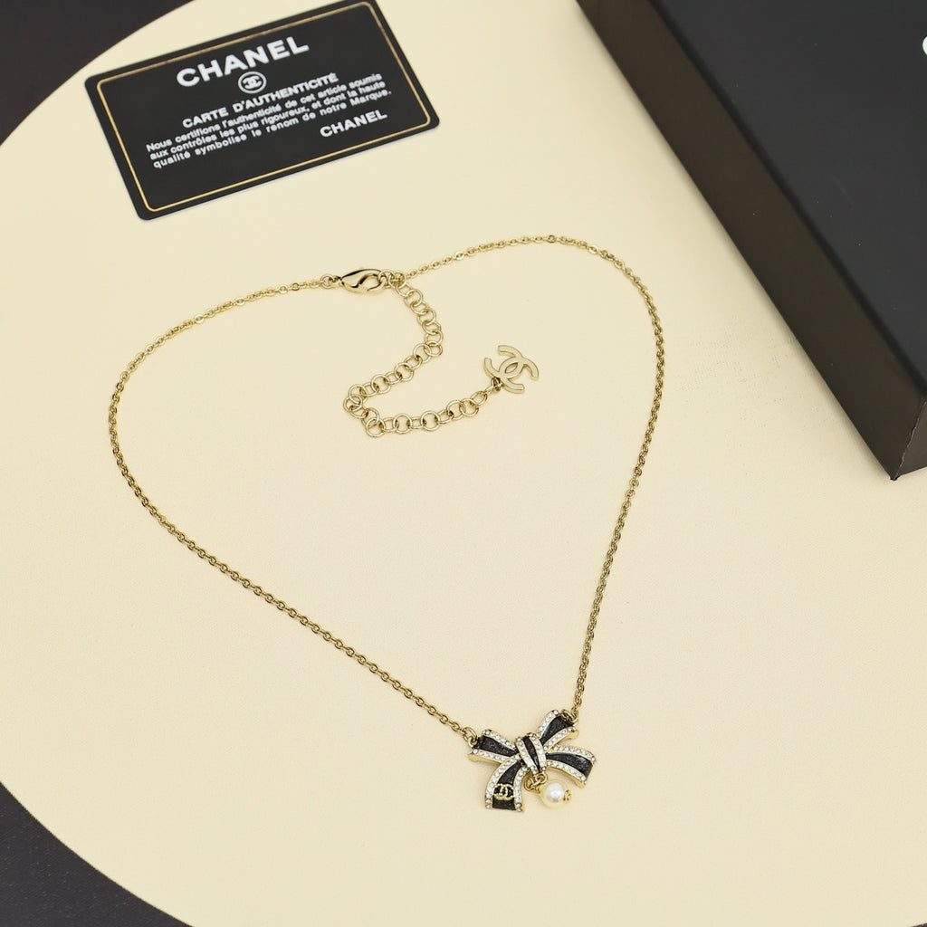 Gold necklace with ribbon bow pendant and pearl, with small logo charm