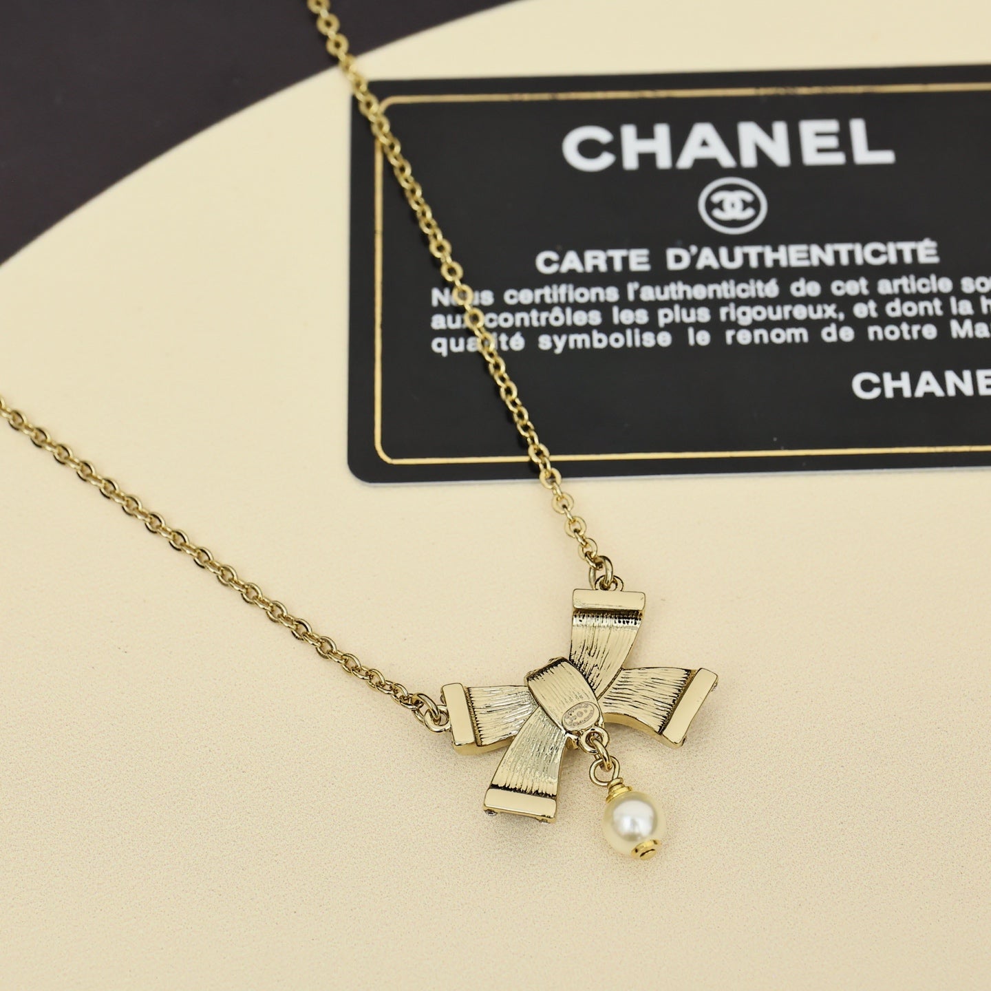 Chanel necklace with gold chain and small pearl charm with ribbon bows