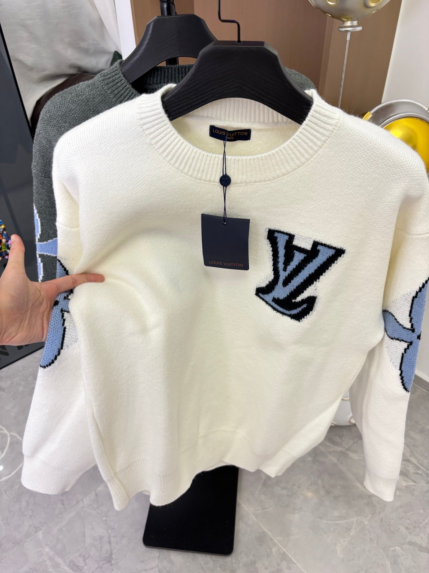 Off-white knit sweater on hanger with navy LV logo and blue sleeve graphics