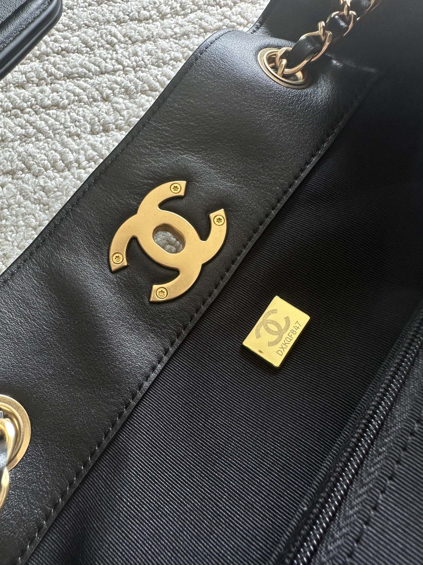 Chanel CC logo patch and small leather tag on black quilted bag