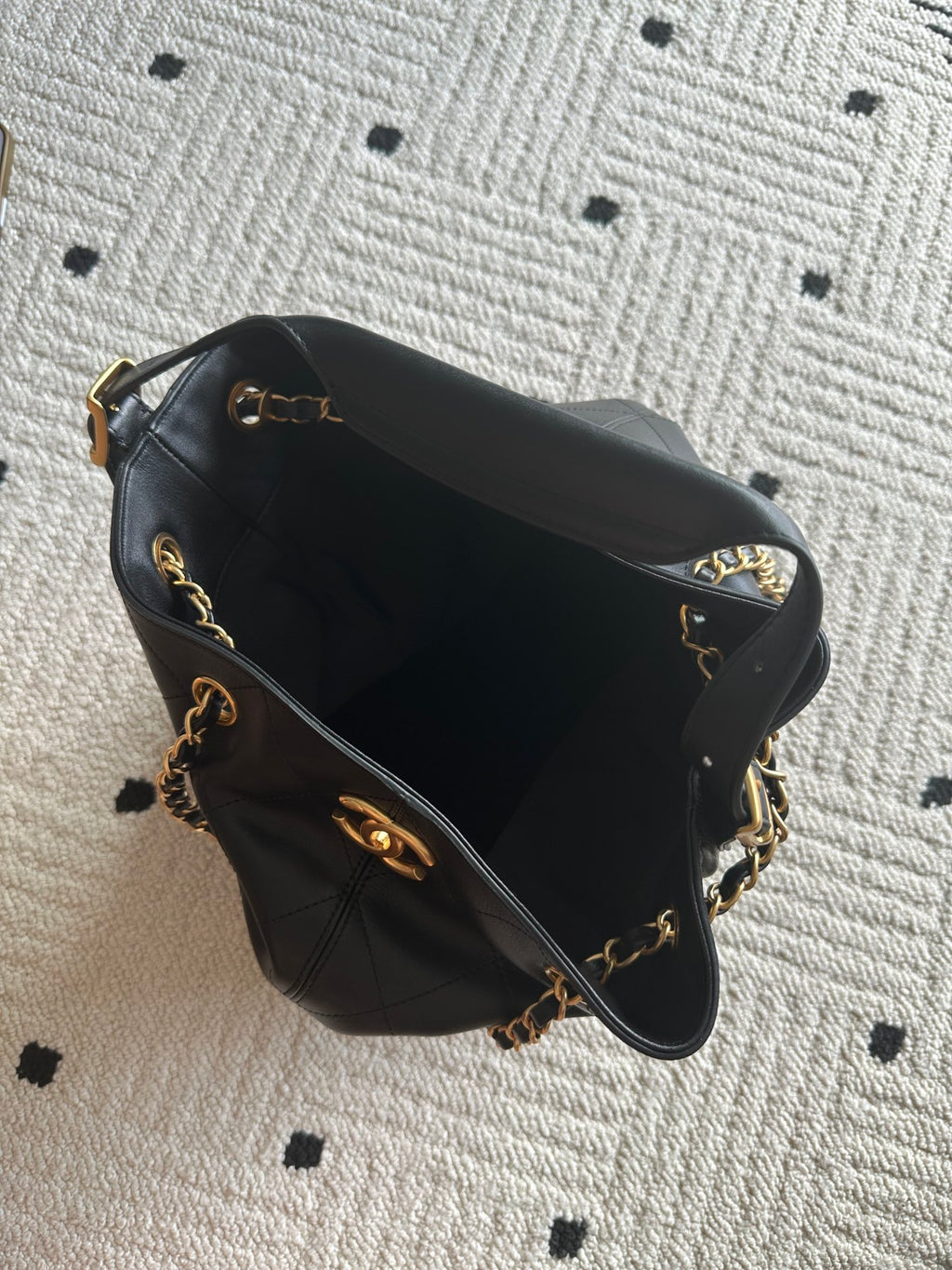 Chanel quilted leather bucket bag with open top, black lining, and gold chain trim