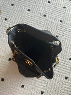 Chanel quilted leather bucket bag with open top, black lining, and gold chain trim