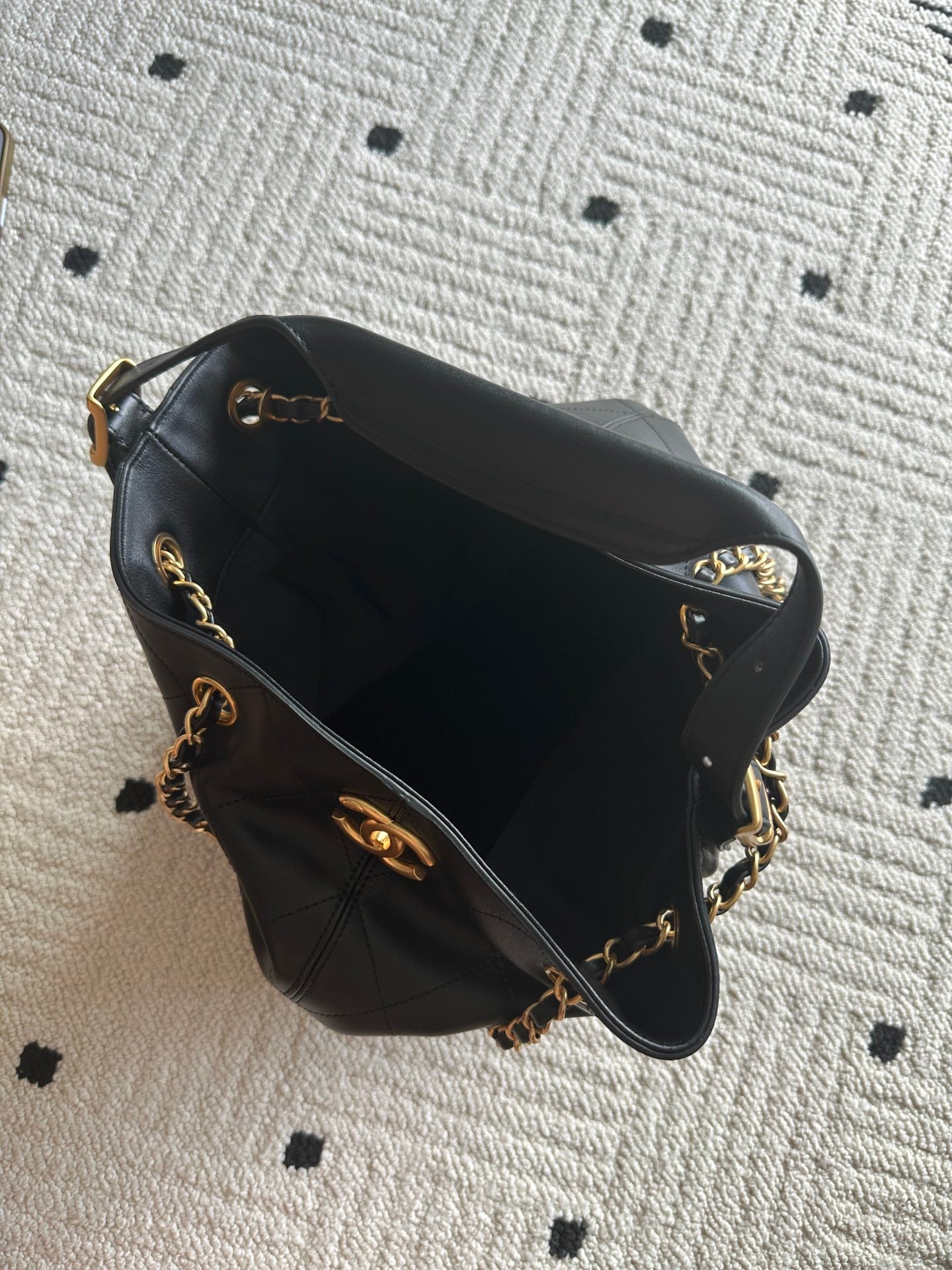 Chanel quilted leather bucket bag with open top, black lining, and gold chain trim