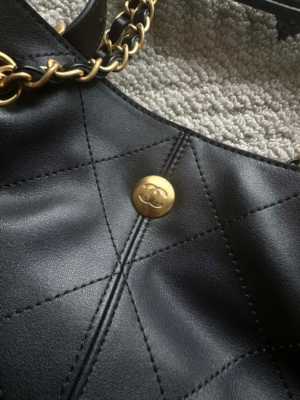 Chanel logo snap button on quilted leather bucket bag front panel
