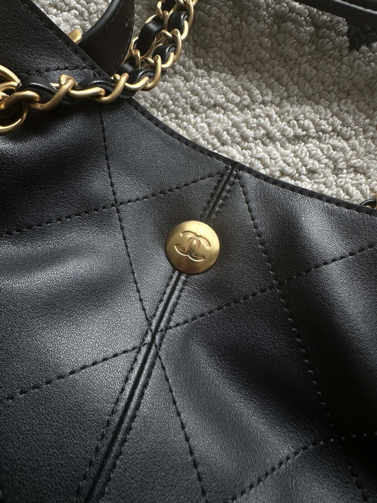 Chanel logo snap button on quilted leather bucket bag front panel