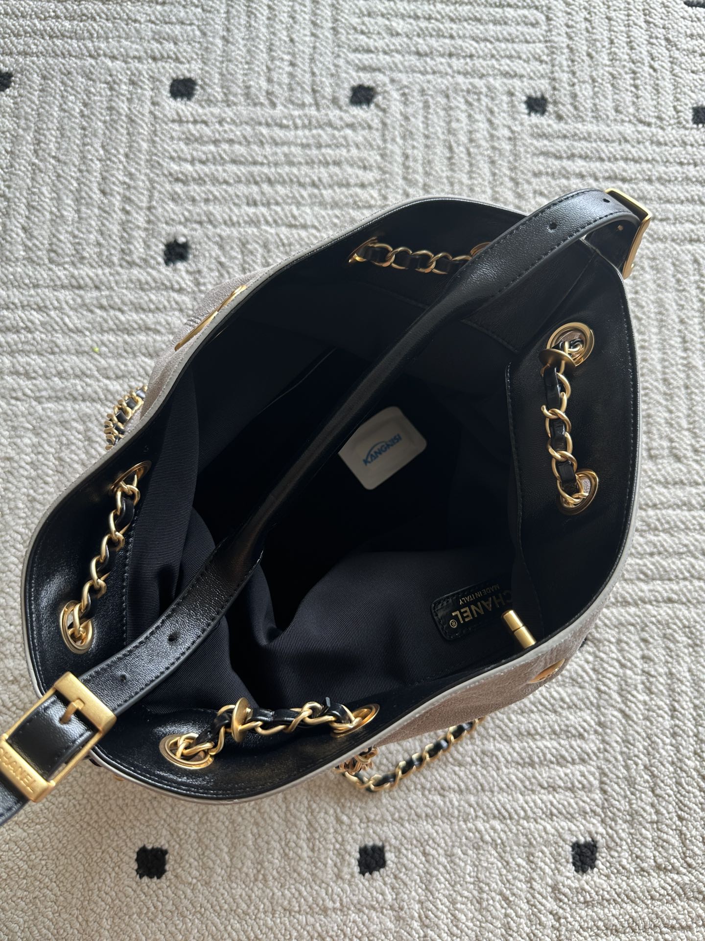 Open black bag interior with light lining, chain strap, and gold hardware