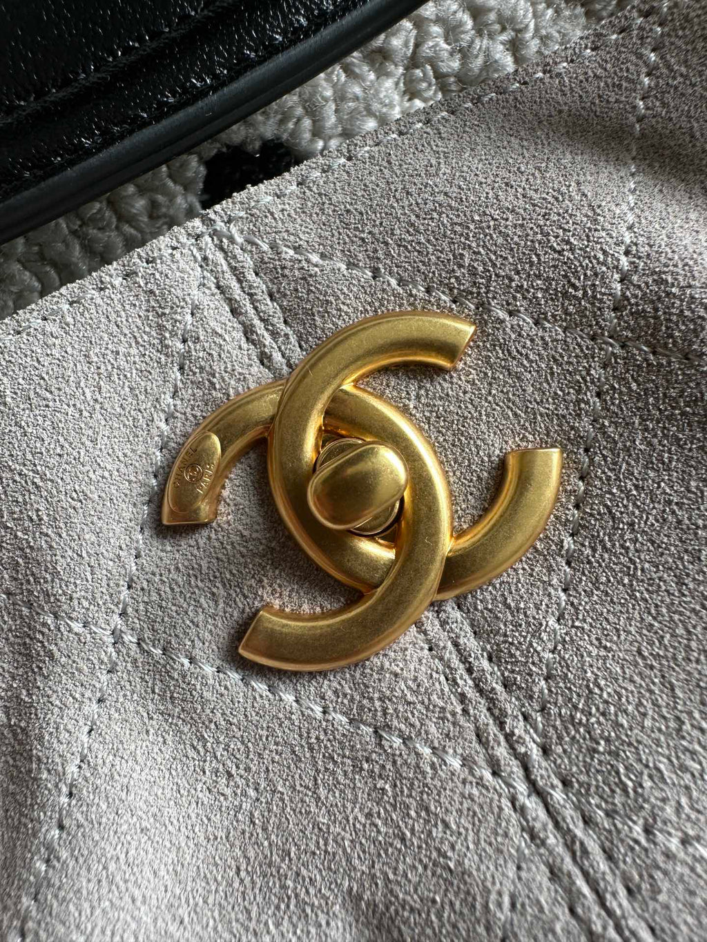 Gold Chanel logo on black leather tab with textured strap