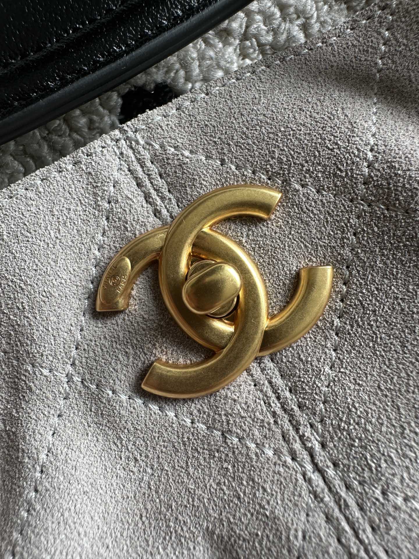 Gold Chanel logo on black leather tab with textured strap
