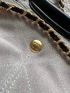 Gold chain and small round Chanel emblem on light fabric interior