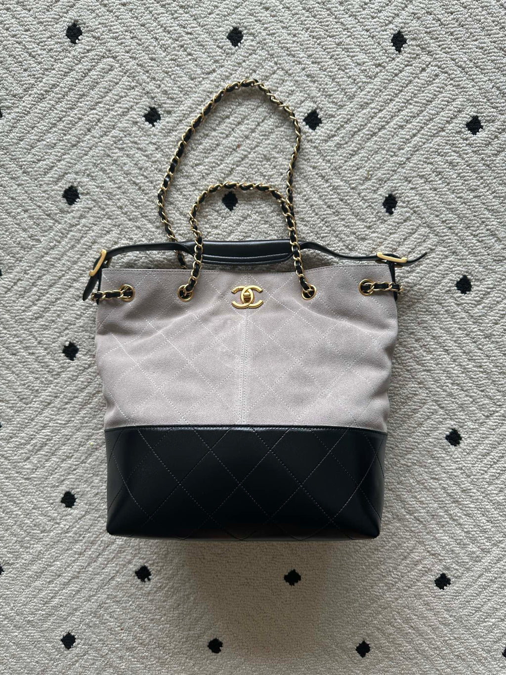 Two-tone tote bag with chain handles and gold clasp; light body, black base