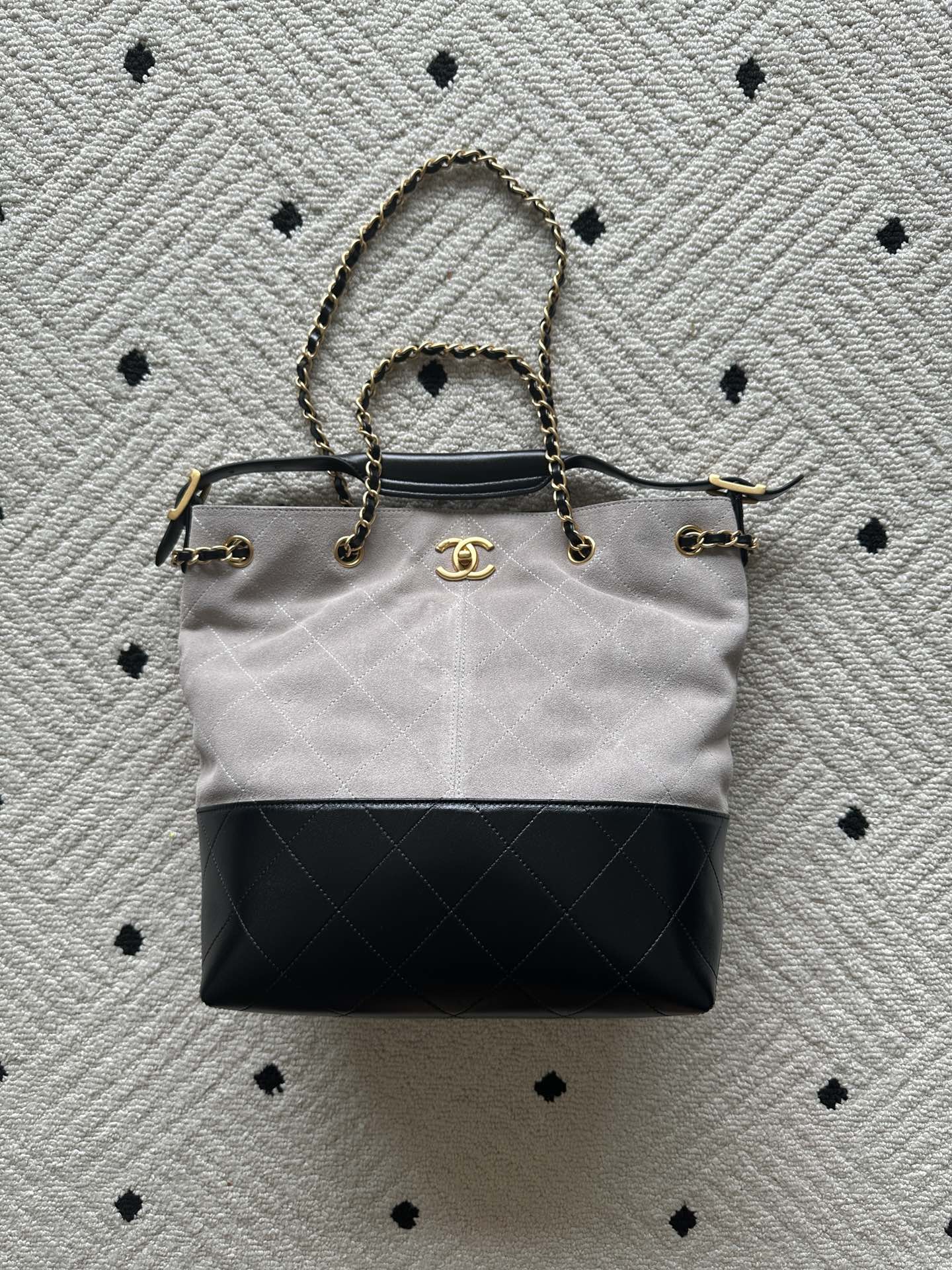 Two-tone tote bag with chain handles and gold clasp; light body, black base