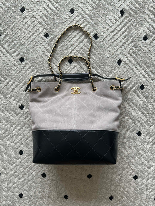Two-tone tote bag with chain handles and gold clasp; light body, black base