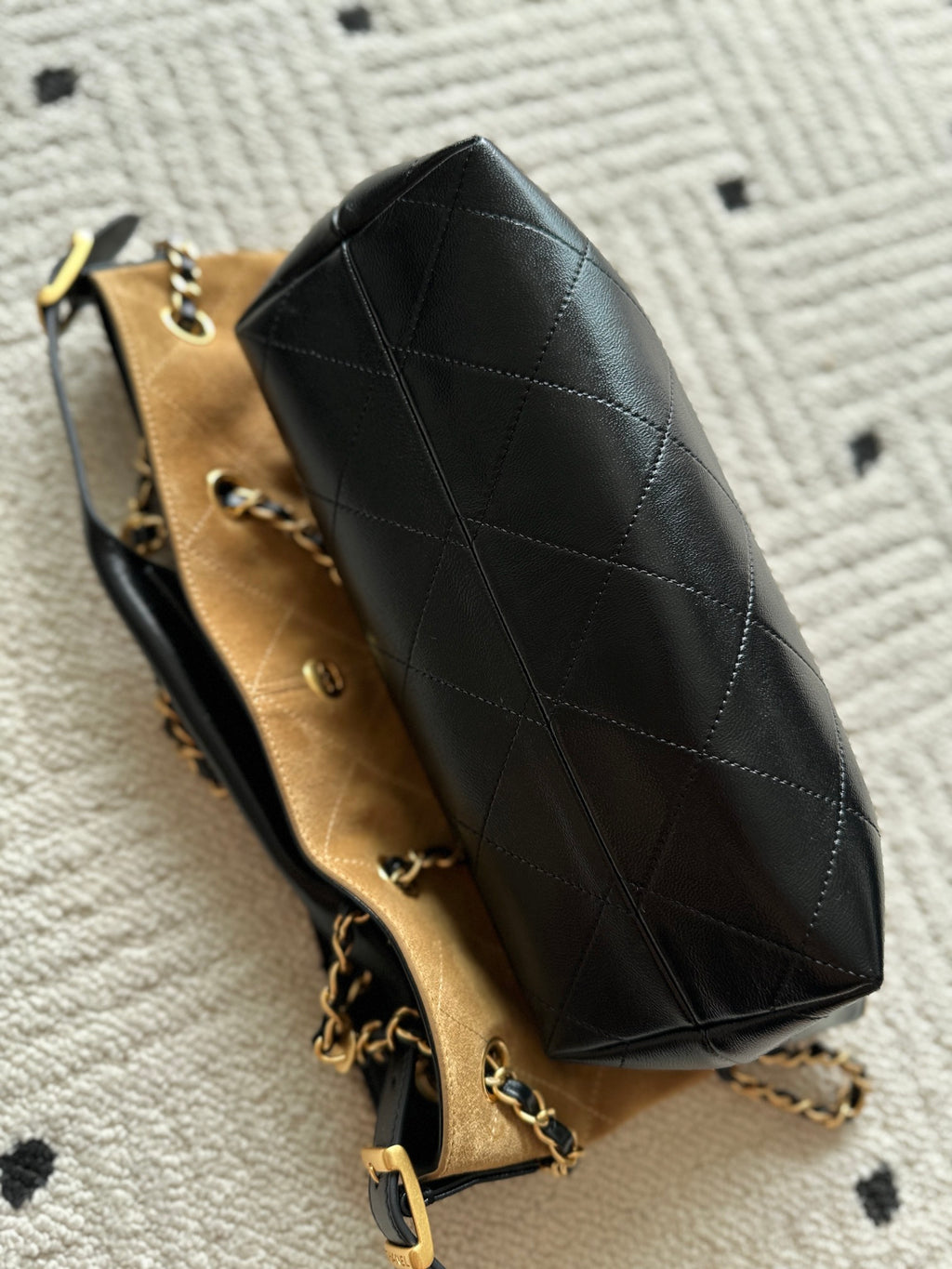 Black quilted tote-style handbag with gold chain strap and beige interior lining.