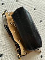 Black quilted tote-style handbag with gold chain strap and beige interior lining.