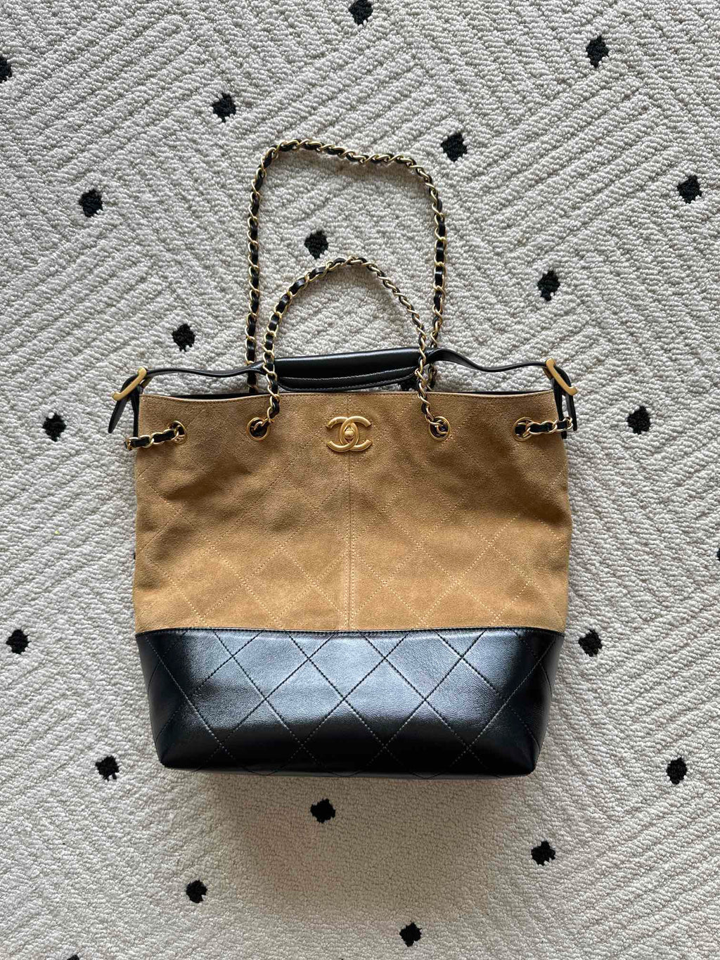 Two-tone handbag with top handle, gold chain straps, beige canvas and dark blue base.