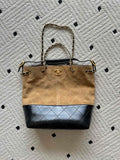 Two-tone handbag with top handle, gold chain straps, beige canvas and dark blue base.