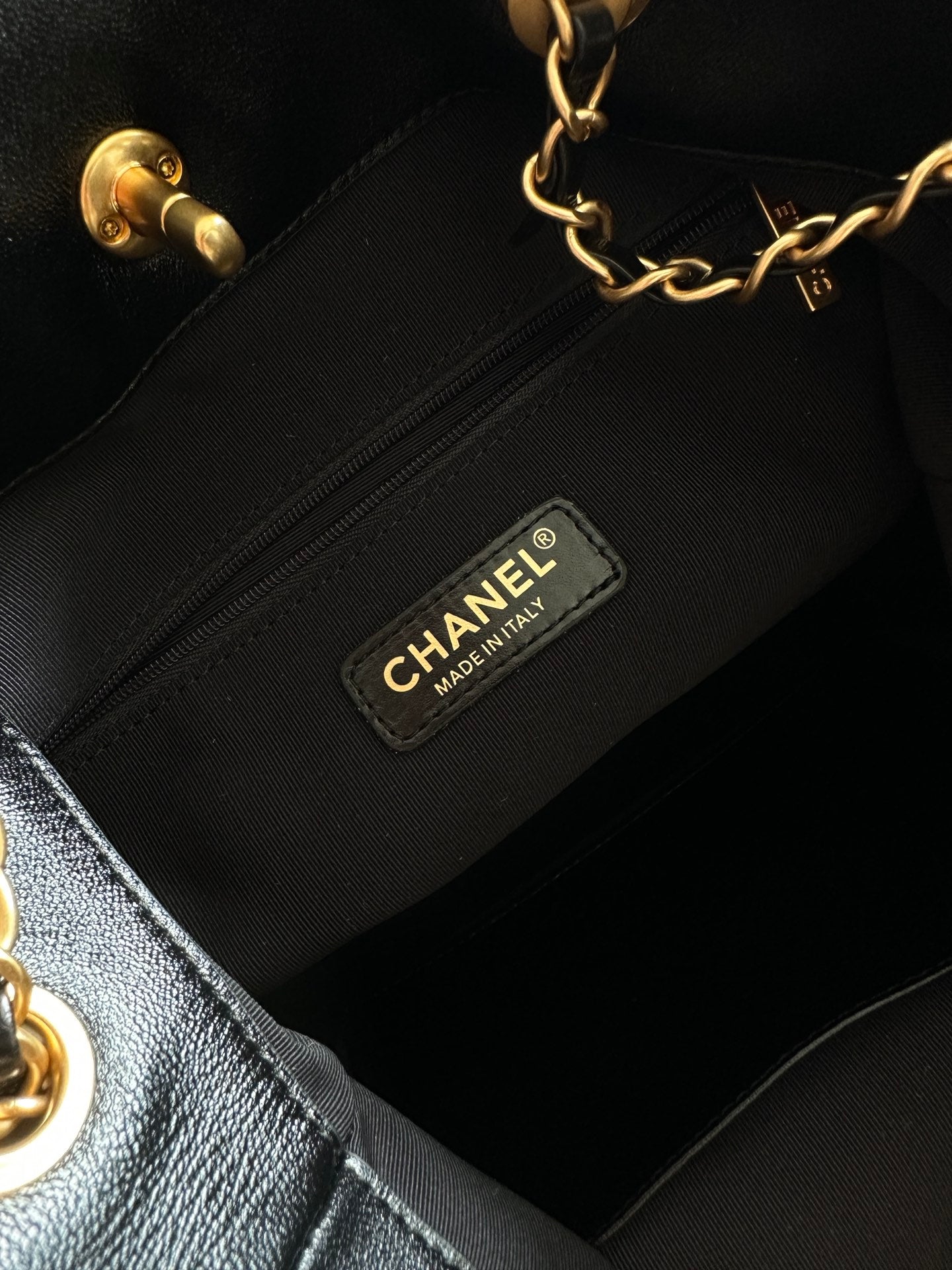 Inside view of black handbag with CHANEL fabric label on interior zip pocket.