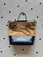 Two-tone handbag with shoulder strap, gold chain detail, beige canvas and dark blue bottom.