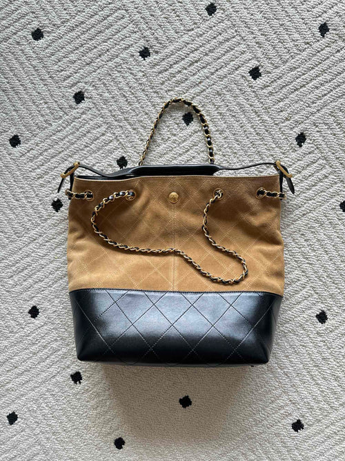 Two-tone handbag with shoulder strap, gold chain detail, beige canvas and dark blue bottom.