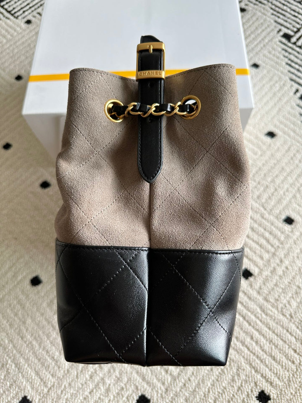 Chanel handbag with taupe upper and black bottom, quilted front, chain strap loop, gold clasp.