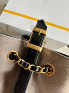 Chanel handbag strap detail with black leather, gold chain link, and CHANEL hardware.