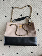 Chanel handbag front view in taupe and black with quilted stripe, chain handle, CC logo.