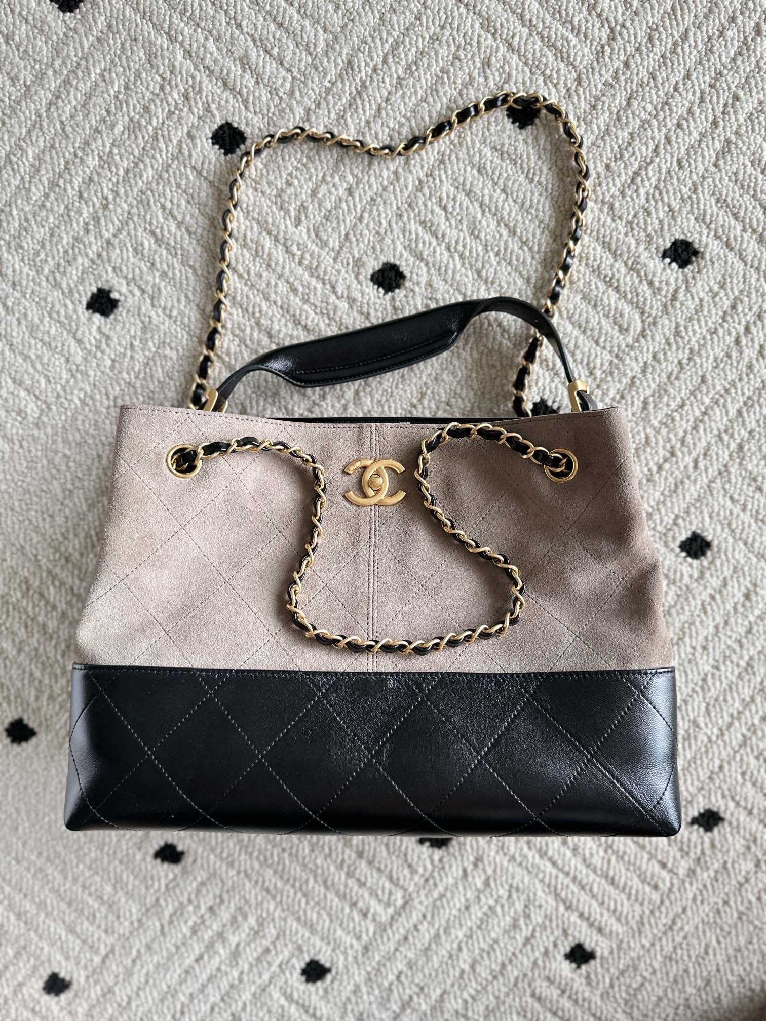 Chanel handbag front view in taupe and black with quilted stripe, chain handle, CC logo.