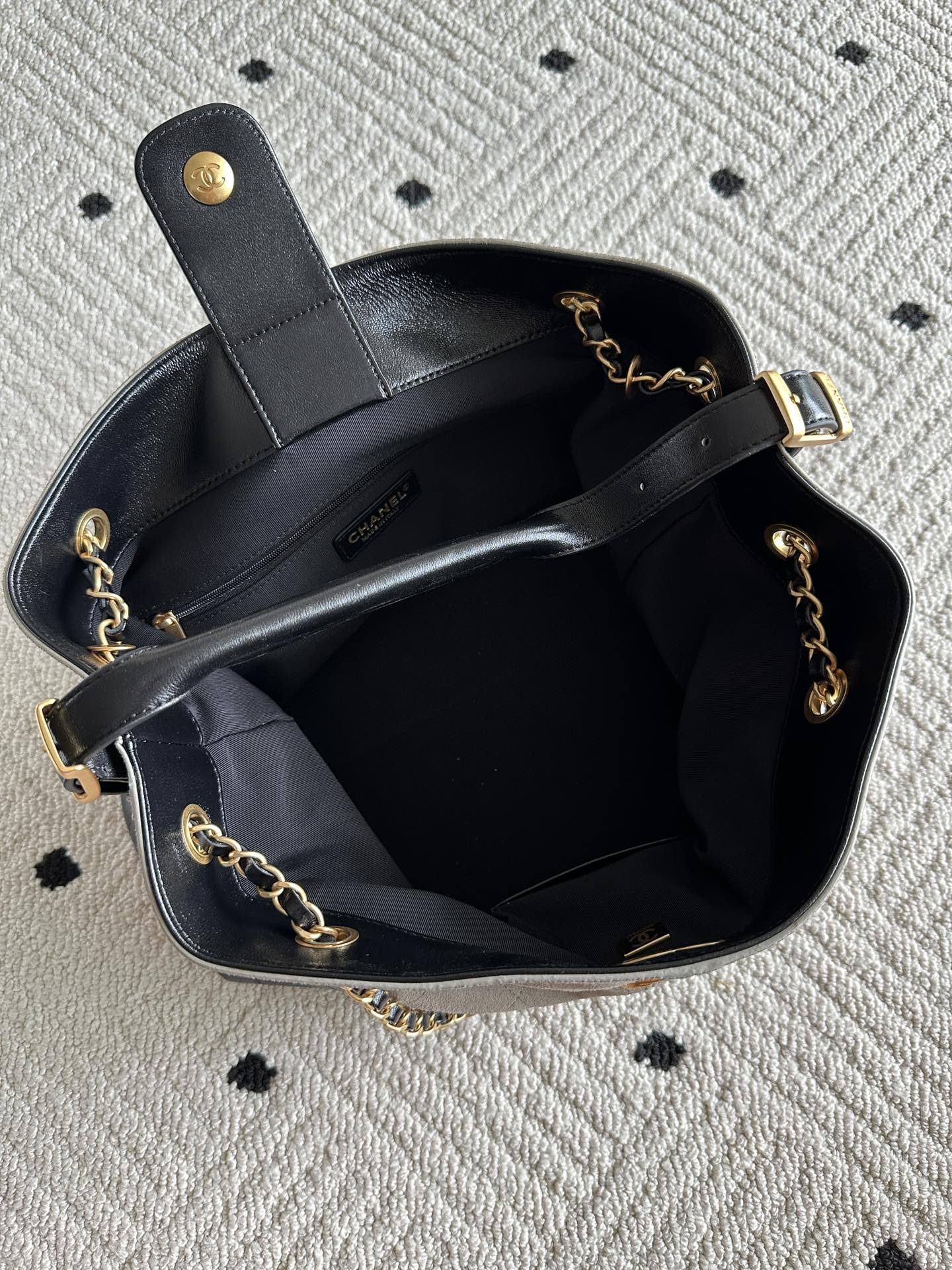 Chanel handbag open top with black interior, chain shoulder straps, gold-tone hardware, CC detail.