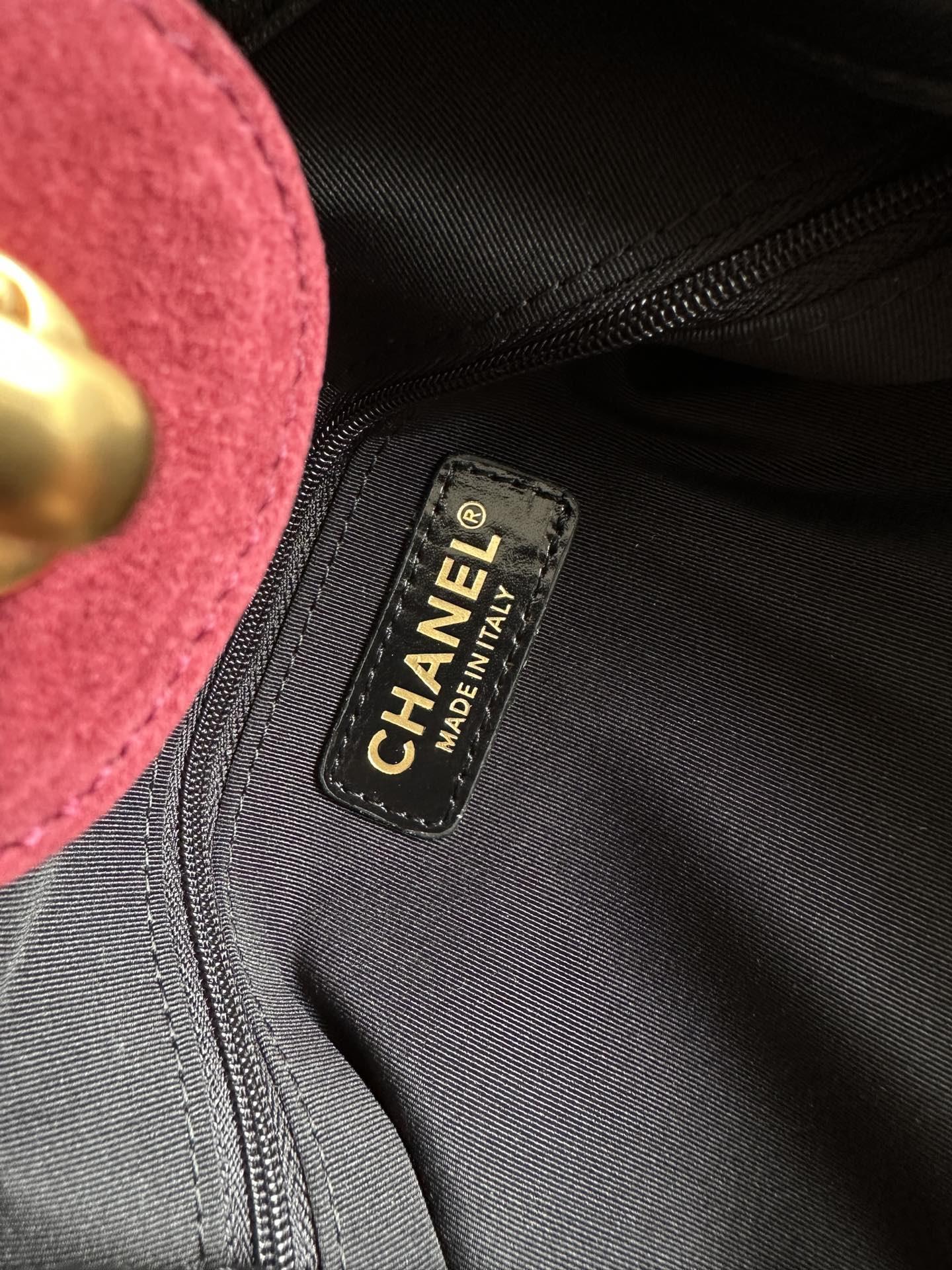 Black interior tag inside burgundy handbag with Chanel made in Italy text