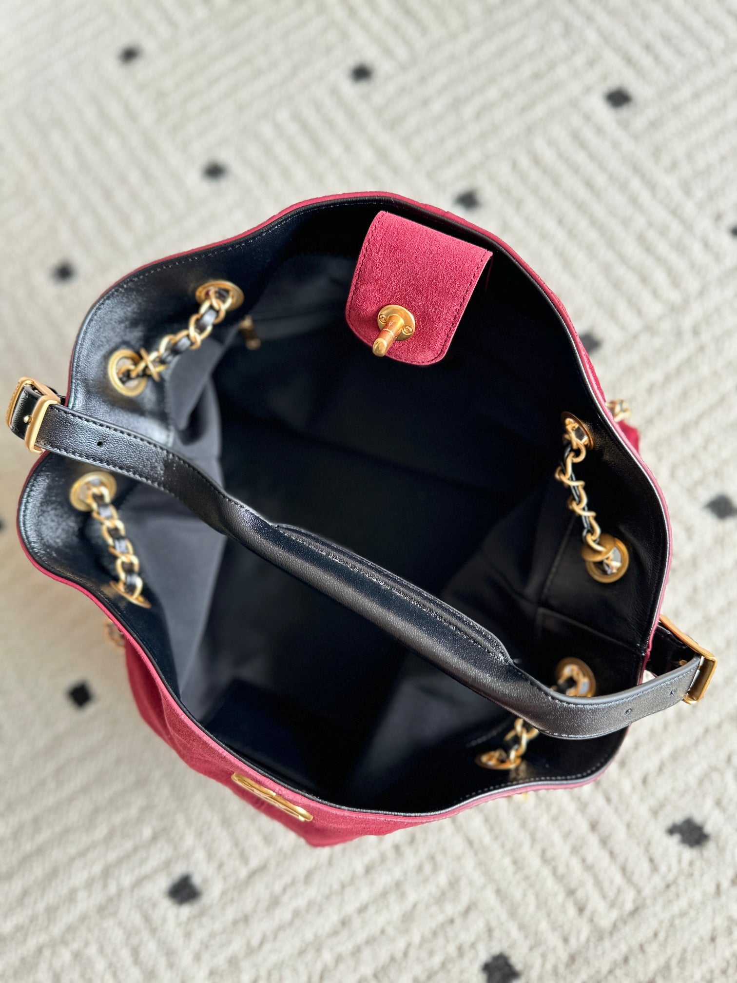 Open burgundy and black handbag with interior lining and gold-tone chain details