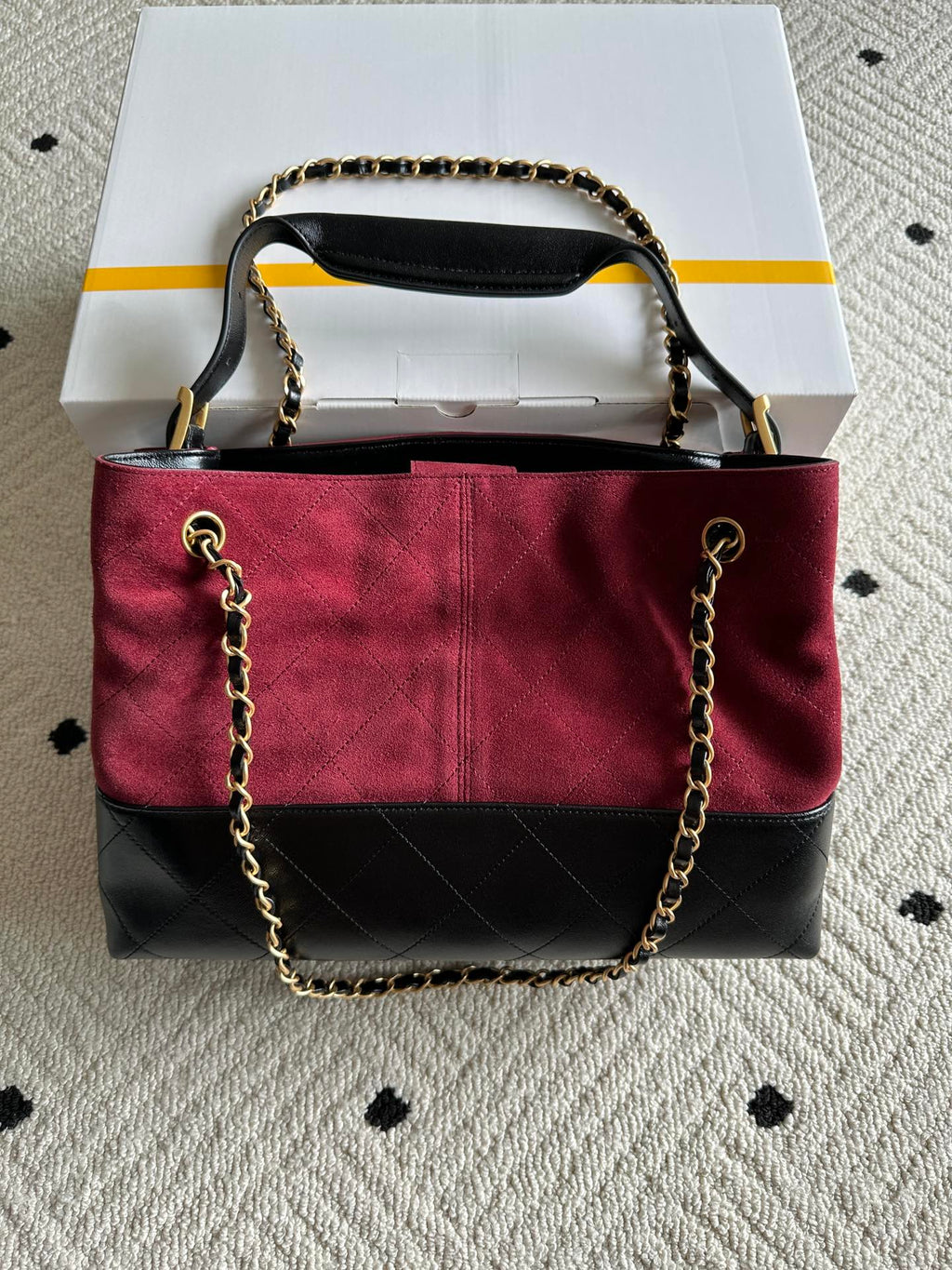 Burgundy and black handbag with top handle and gold-tone chain shoulder strap