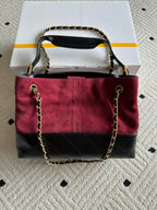 Burgundy and black handbag with top handle and gold-tone chain shoulder strap