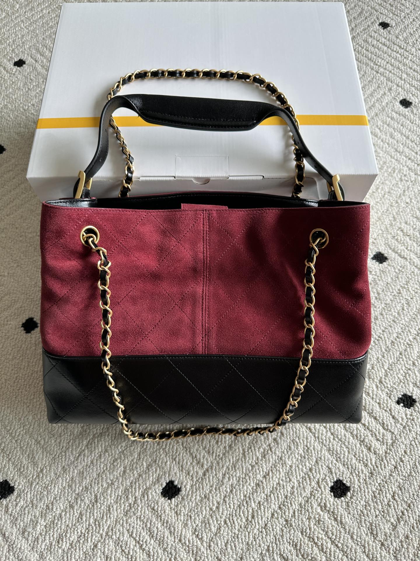 Burgundy and black handbag with top handle and gold-tone chain shoulder strap