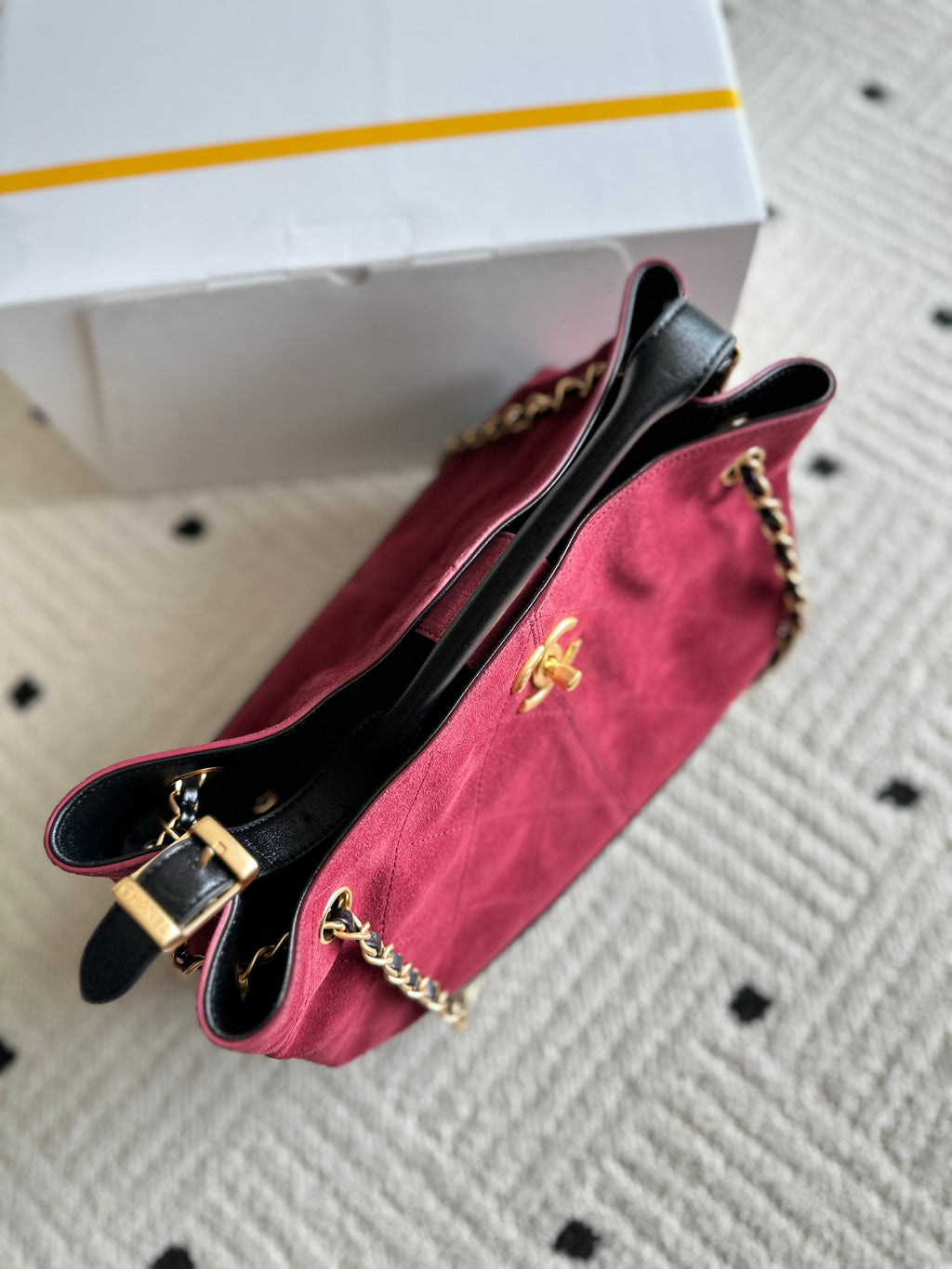 Burgundy and black handbag with chain strap and front logo medallion, side view