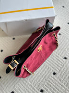Burgundy and black handbag with chain strap and front logo medallion, side view