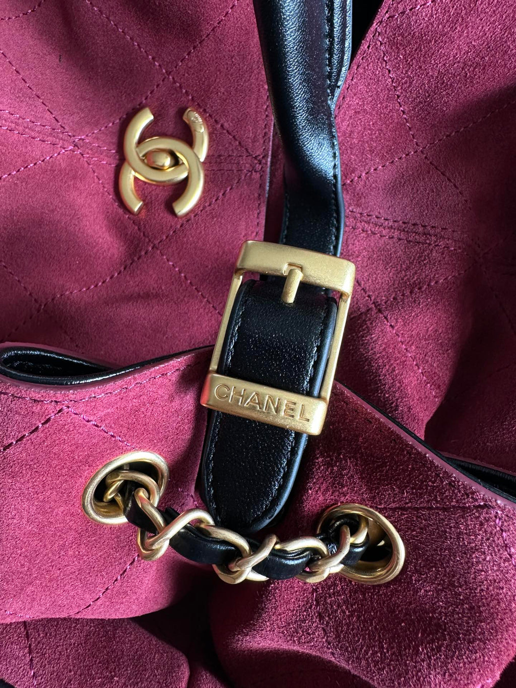 Burgundy handbag close-up of gold-tone logo and black chain strap hardware