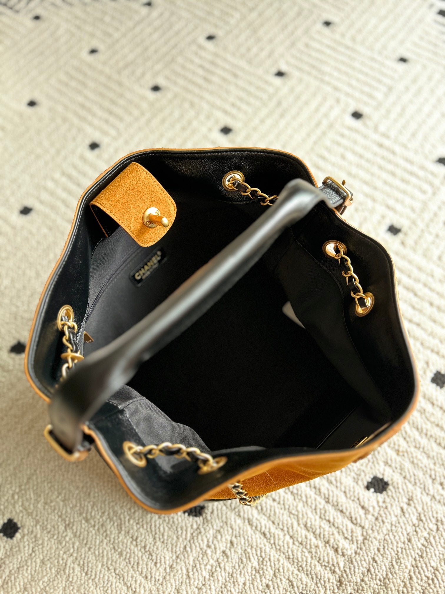 Two-tone shoulder bag opened to show black interior and gold chain accents at edges.