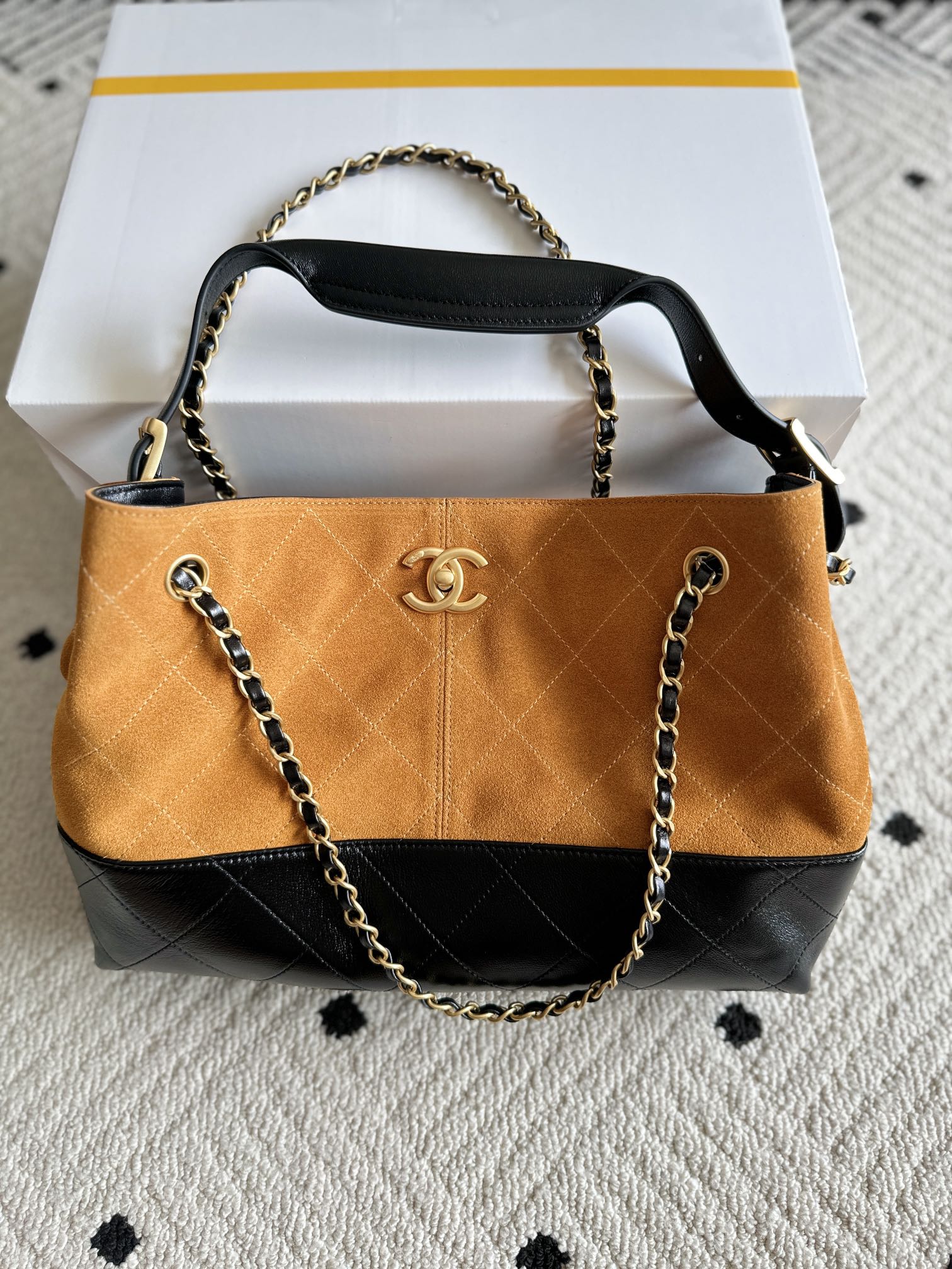 Two-tone shoulder bag with gold chain strap; orange front panel and Chanel emblem center.