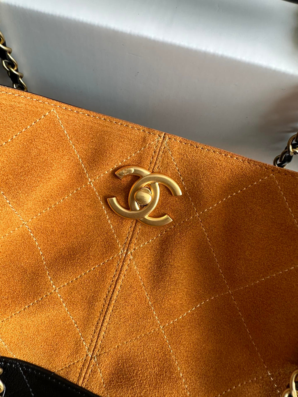 Orange quilted bag panel with gold Chanel emblem hardware centered on the flap.