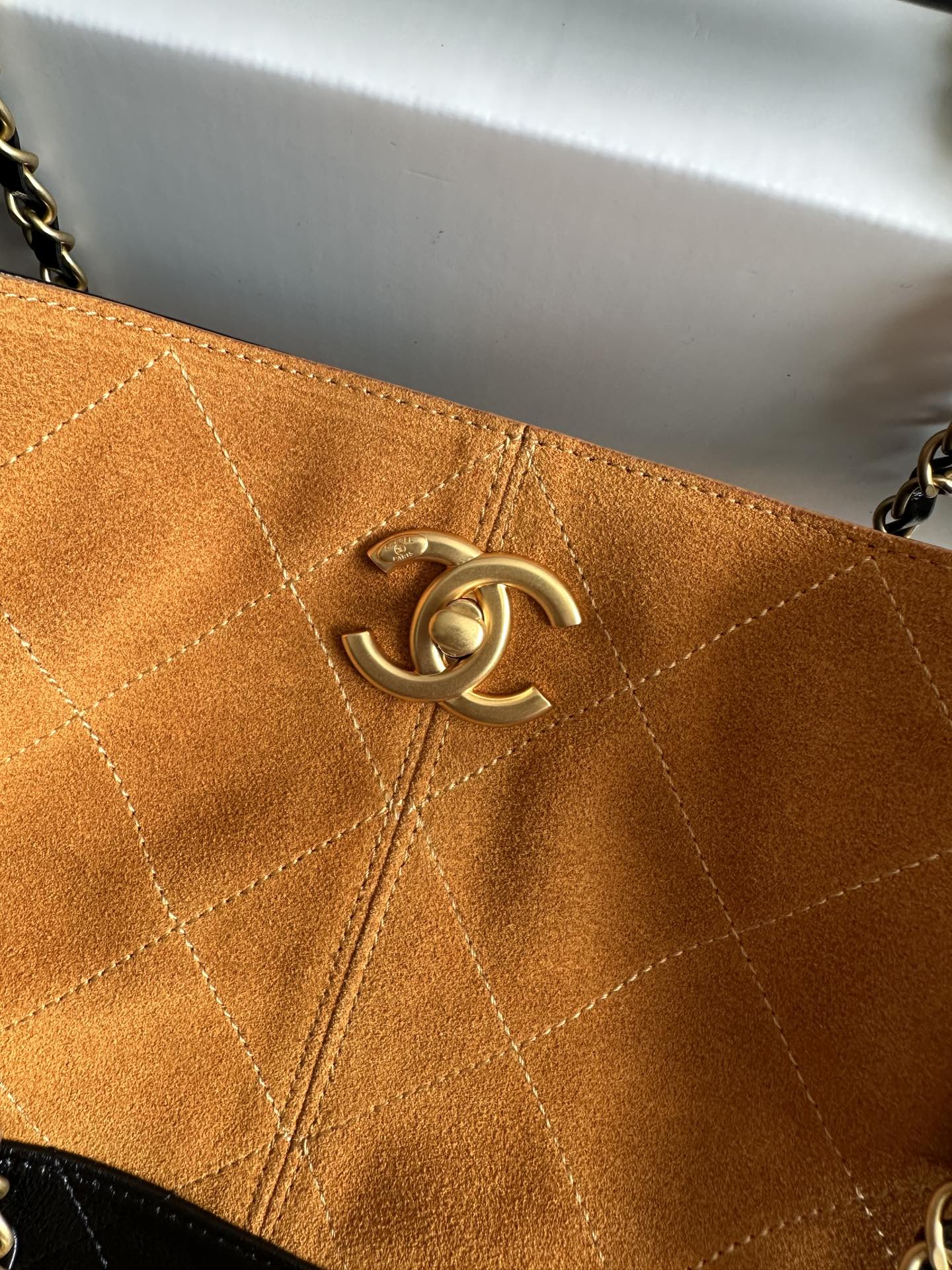 Orange quilted bag panel with gold Chanel emblem hardware centered on the flap.
