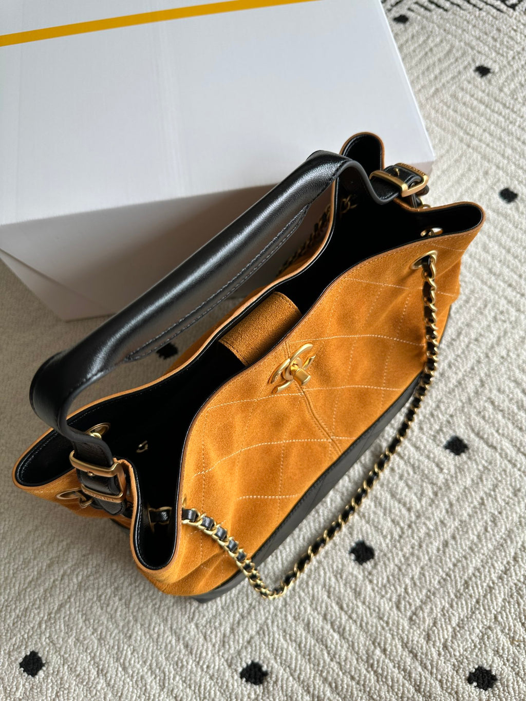 Two-tone shoulder bag with black top handle, orange body, and gold chain strap detail.
