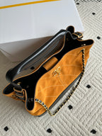 Two-tone shoulder bag with black top handle, orange body, and gold chain strap detail.