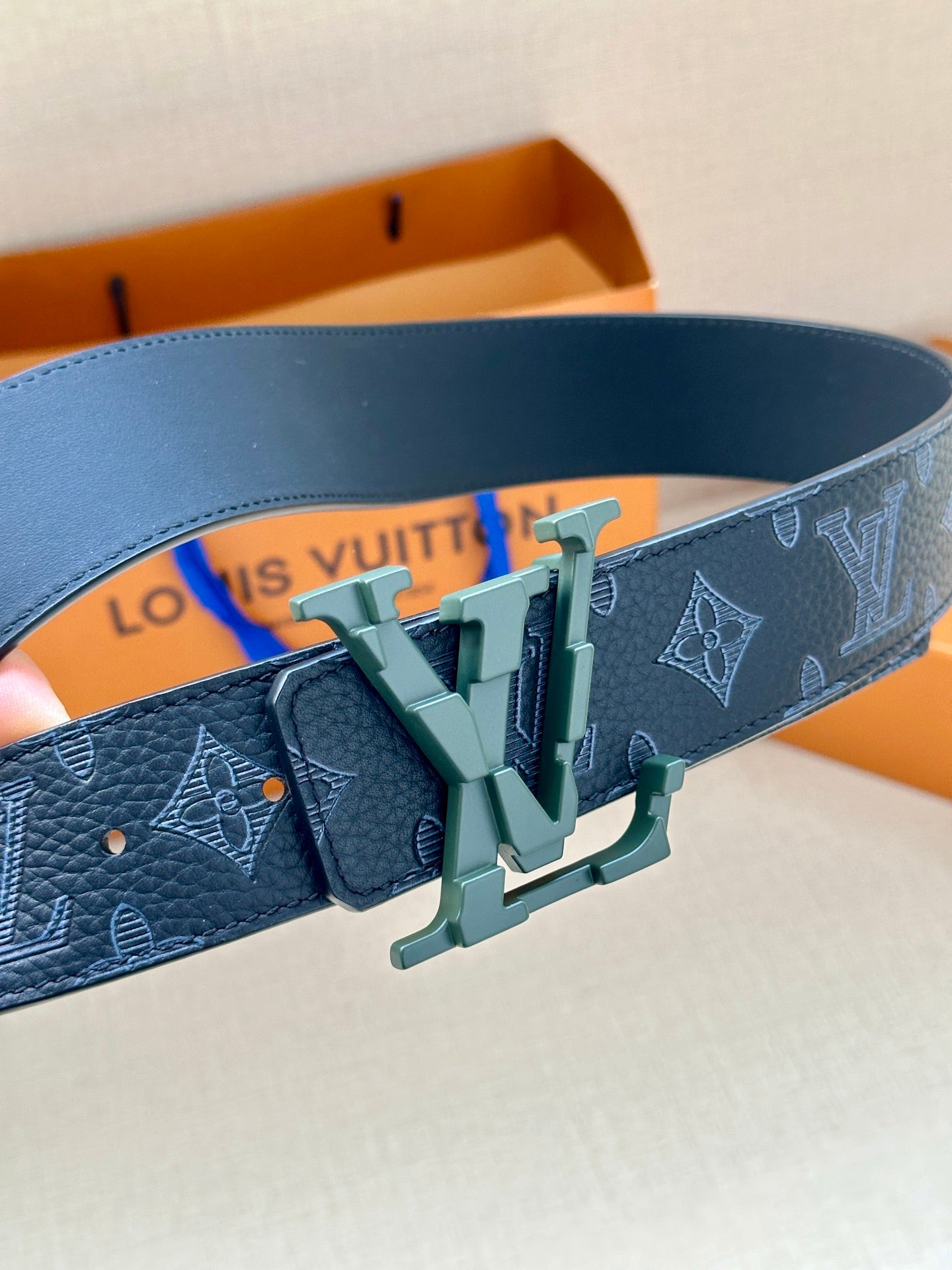 Dark blue monogram belt close-up with green buckle hardware